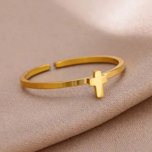 Close-up of golden stainless steel open ring featuring a minimalist cross design on silk