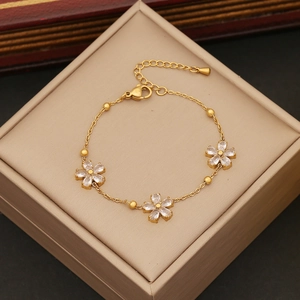 Gold stainless steel flower bracelet with white cubic zirconia crystals on beige box