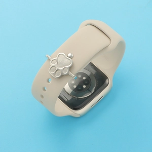 Close-up of a silver paw print charm accessory on a beige silicone smartwatch strap