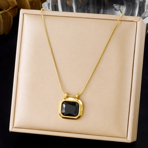 Close-up of square black gemstone pendant with gold snake chain on a jewelry cushion