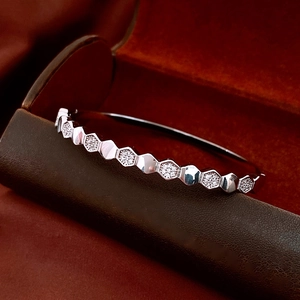 Macro view of silver hexagonal honeycomb bangle with zircon pavé on luxury velvet box