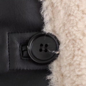 Detail of black faux leather texture with beige fleece lining and a single black button