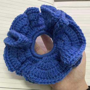 Detail of blue crochet ruffle hair tie showing handmade knit texture and flower design