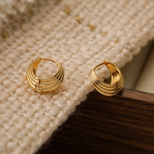 Golden geometric hoop earrings with spiral texture on a soft knitted background