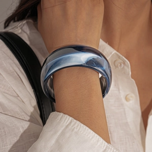 Detail of a deep blue acrylic resin bangle with white ink smoke patterns on a model