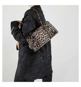 Detail of leopard print baguette bag with heart charm worn by model in black suit