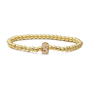 Detailed close-up of golden beaded elastic bracelet featuring a sparkling zircon S charm