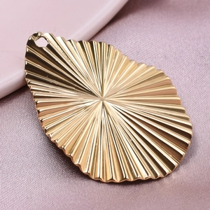 Gros plan d'un pendentif goutte en acier inoxydable doré 18 carats à texture radiale