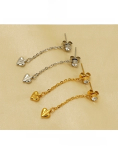 Macro detail of gold and silver heart tassel earrings on silk background