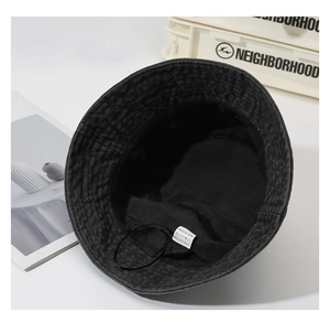 Detail of a black cotton bucket hat showing the 100% cotton wash label and inner texture