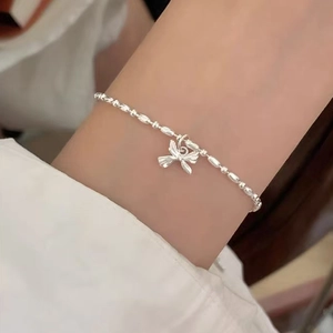 Silver beaded bracelet with butterfly pendant worn on wrist for minimalist luxury style