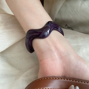 Irregular purple acrylic wave bangle with marble texture worn on wrist for a modern look