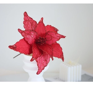 Close-up of red artificial Christmas flower with sequins in a white ceramic vase