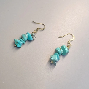 Detail view of handmade bohemian dangle earrings with turquoise crushed stones and gold hooks