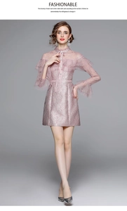 Détail de robe en dentelle brodée rose avec manches volantées et col montant rétro