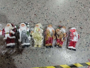 Detailed close-up of six different standing Santa Claus dolls in clear plastic packaging