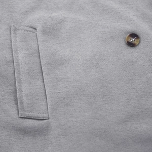 Detail of grey trench coat showing side pocket and amber textured button closeup