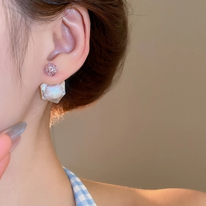Close-up of model wearing geometric drop earrings with pink crystal ball and clear pendant