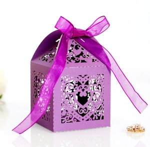 Close-up of purple laser-cut wedding favor box with heart patterns and silk ribbon bow