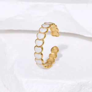 Minimalist gold heart ring with white enamel accents on a textured stone background