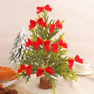 Mini artificial Christmas tree with red bows and a natural wooden base for table decor