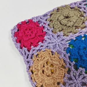 Close-up of colorful handmade crochet tote bag featuring intricate floral knitting patterns