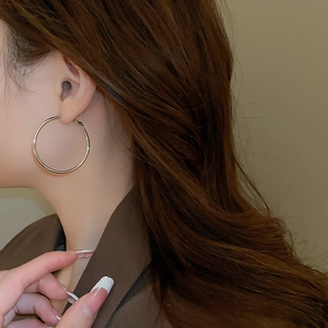 Close-up of minimalist silver hoop earring on model showing sleek metallic finish