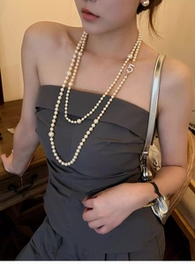 Detail of elegant double-layered pearl necklace with golden zircon number 5 pendant on model