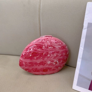 Detailed view of pink marble pattern oval clutch with a glossy finish on fabric background