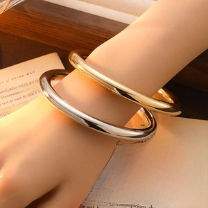 Polished gold and silver minimalist open bangles worn together on a vintage book