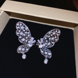 Détail de boucles d'oreilles papillon argentées avec zircons et perles en goutte