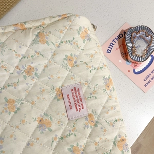 Macro detail of floral quilted cotton makeup bag with pastel flowers and soft stitching