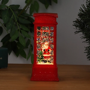 Close-up of lighted red Christmas telephone booth with Santa Claus inside and swirling glitter
