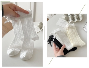 Detail of lace frill and bow on knit cotton socks in white, black, and cream colors