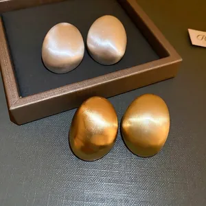 Brushed metal geometric oval earrings in matte gold and silver finish with elegant texture