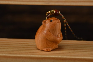 Nahaufnahme eines handgeschnitzten Hamster-Anhängers aus Holz mit geflochtener Kordel