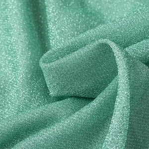 Détail du tissu en maille brillante vert menthe avec paillettes métalliques pour ensemble