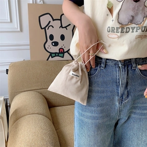 Detail of beige corduroy drawstring pouch with white woven label held by hand
