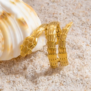 Close-up of golden snake ring with textured scales on a shell and sand background