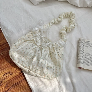 Gros plan d'un sac cabas en dentelle florale avec bandoulières plissées sur fond blanc