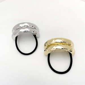 Detail of gold and silver alloy hair ties featuring irregular hammered metal textures
