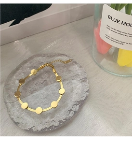 Nahaufnahme der goldenen Schlangenkette mit runden Pailletten auf einer Glastafel