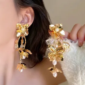 Detail of gold flower tassel earrings with white pearls and sparkling rhinestone accents