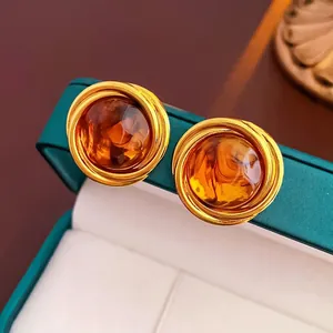 Macro detail of vintage tiger eye stone earrings with gold wire wrap in a green velvet box