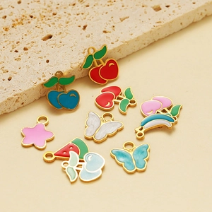 Assorted stainless steel fruit and butterfly enamel pendants on beige stone background