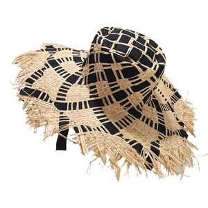 Two-tone raffia sun hat with black woven pattern and frayed edges for beach vacation
