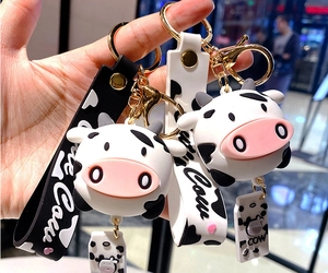 Close-up of cute black and white cow keychain with printed lanyard and golden metal ring