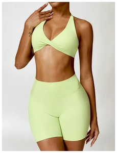 Close-up of seamless light green yoga set featuring high-waist shorts and cross halter bra
