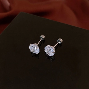 Macro shot of zircon stud earrings in silver settings on a dark reflective stand