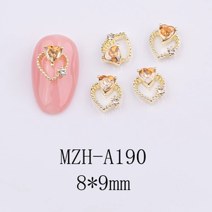 Detail of 8x9mm golden hollow heart nail charm with amber orange gem and tiny white diamonds